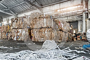 Dump pile of used shreded paper wrap and document against bales of compressed cardboard collected for recycling and