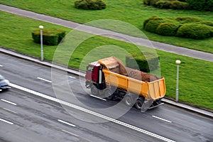 Dump truck carries sand along a road in a city. View from above.