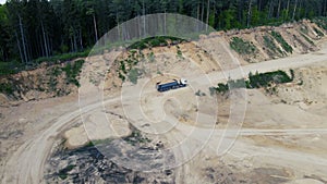 Dump truck transported sand from the open pit. Truck with tipper semi trailer working in quarry. Arial view of the opencast mine.