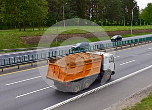 Dump truck transports sand along a road in a city. Object in motion, soft focus, possible graininess