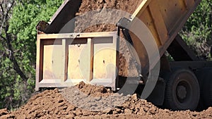 Dump truck unload soil to the ground for highway construction. Heavy Industrial Machines Build New Road.