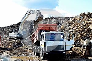 Dump truck unloading of broken concrete slabs demolition waste on landfill. Reuse concrete.