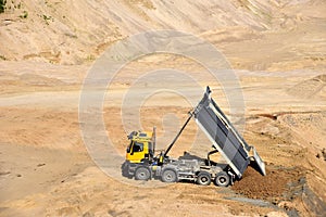 Dump truck unloading earth sand in quarry. Recovering the landscape around the open pit. Process of restoring land. Mine