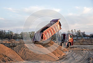 Dump truck unloading earth sand for road construction or for foundation work