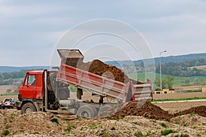Dump truck unloading soil at construction site