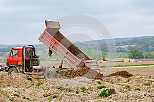 Dump truck unloading soil at construction site