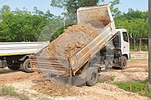 Dump truck unloading soil at construction site