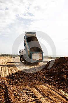 Dump truck unloads clay soil for the construction of a new highway. Clay for laying the foundation of a new road
