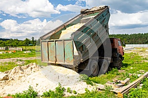 The dump truck unloads sand. The truck dumped the cargo. Sand and gravel. Construction site, materials warehouse