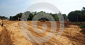 Dump trucks and bulldozers clear land for a new roadway