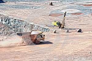 Dumper truck driving around in open pit mine of porphyry rock.