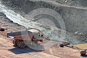 Dumper truck driving around in open pit mine of porphyry rock.