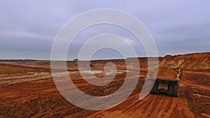 Dumper truck moving along sand quarry. Aerial view of dump truck