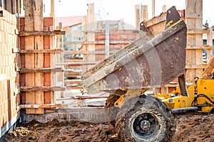 Dumper truck unloading gravel, sand and stones at construction site. Bricklayering and working at construction site