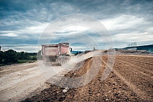 dumper trucks working on highway construction site, loading and unloading gravel and earth. heavy duty machinery activi