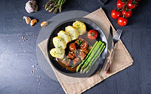 A dumplings with beef goulash and green asparagus