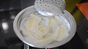 Dumplings are boiled in boiling water in a pan on an induction stove
