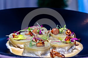 Dumplings with chanterelle mushrooms on a black plate