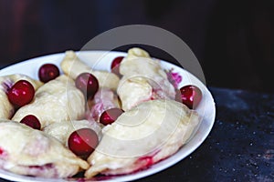 Dumplings with cherries in a plate on a dark retro background