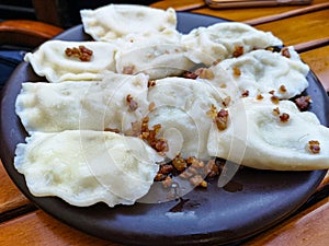 Dumplings with greaves on a dark plate on a wooden table
