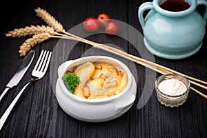 Dumplings with potatoes and cracknel on black wooden background photo