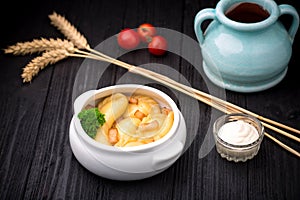Dumplings with potatoes and cracknel on black wooden background photo