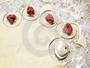 Dumplings raw and food dough on marble table, traditional making of Russian pelmeni or dumplings