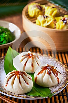 Dumplings set Xiao long bao and Shao mai in bamboo steaming basket and chopsticks on bamboo mat. Selective focus. Asian food menu