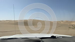 Dune driving in desert. White SUV car off road travel in Africa.