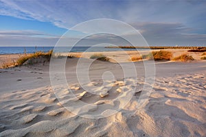 Dunes on the coast of the Baltic Sea, beach, white sand, grass, blue sky, Kolobrzeg, Poland.