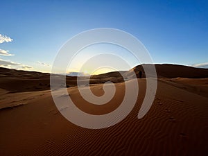 Dunes in the Sahara desert, Merzouga, panoramic view. Morocco. Sunset. A girl walking on a sand dune