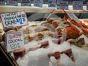 Dungeness crab and shrimp cocktails sitting in ice store front at a seafood fishermans market