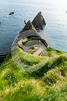 Dunquin or Dun Chaoin pier, Ireland\'s Sheep Highway. Narrow pathway winding down to the pier, ocean coastline, cliffs.