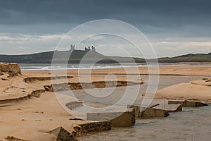 Dunstanburgh Castle in Northumberland, England, with cloudy skies overhead