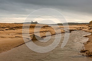 Dunstanburgh Castle in Northumberland, England, with cloudy skies overhead