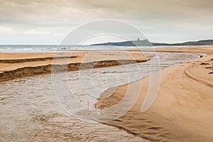 Dunstanburgh Castle in Northumberland, England, with cloudy skies overhead