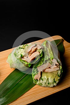 Duo of spring rolls. Cucumber and ham on a banana leaf.