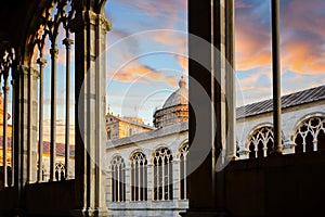 The Duomo Pisa Cathedral dome is visible under a colorful sky from the Camposanto Monumentale in Pisa Italy