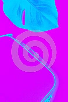 Duotones. neon, Fluorescent handbag and leaf monstera. Vertical