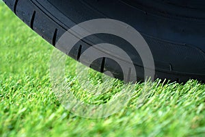 Durable artificial grass lawn concept with wheel tire on the green synthetic turf