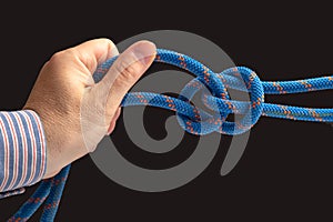 Durable colored rope for climbing equipment on a dark background. knot of braided cable. item for tourism and travel