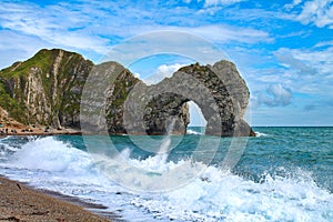Durdle Door rock arch with foamy waves in the foreground