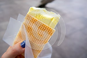 Durian Ice Cream in a waffle in a woman`s hand, made of Durian Durio, asian fruit having strong, smelly odour