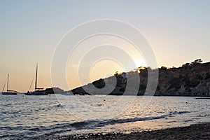 Dusk on a beach in Ibiza, in the Balearic Islands, with the sea and some boats in the background