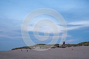 Dusk Descends on Beachgoers Near Coastal Lighthouse