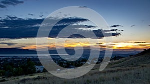 Dusk falls over a sleepy city in a valley with mountains and a lake in the background