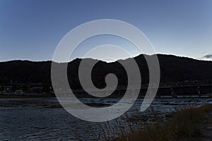 A dusk landscape of Togetsukyo bridge in Kyoto in autumn wide shot