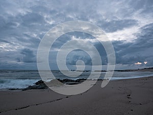 Dusk on the rocky beach with dark, gray, cloudy sky