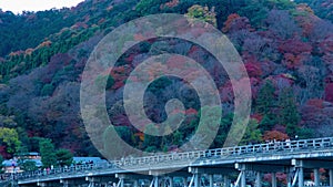 A dusk timelapse of Togetsukyo bridge in Kyoto in autumn telephoto shot panning