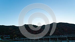 A dusk timelapse of Togetsukyo bridge in Kyoto in autumn wide shot panning